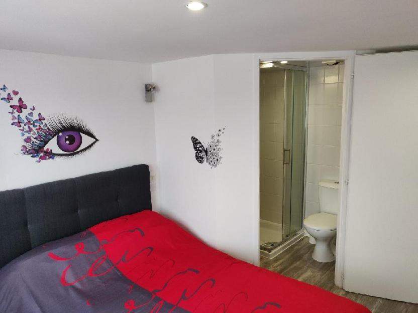um quarto com uma cama vermelha com um olho na parede em Les Gones en Vendée em Saint-Gervais