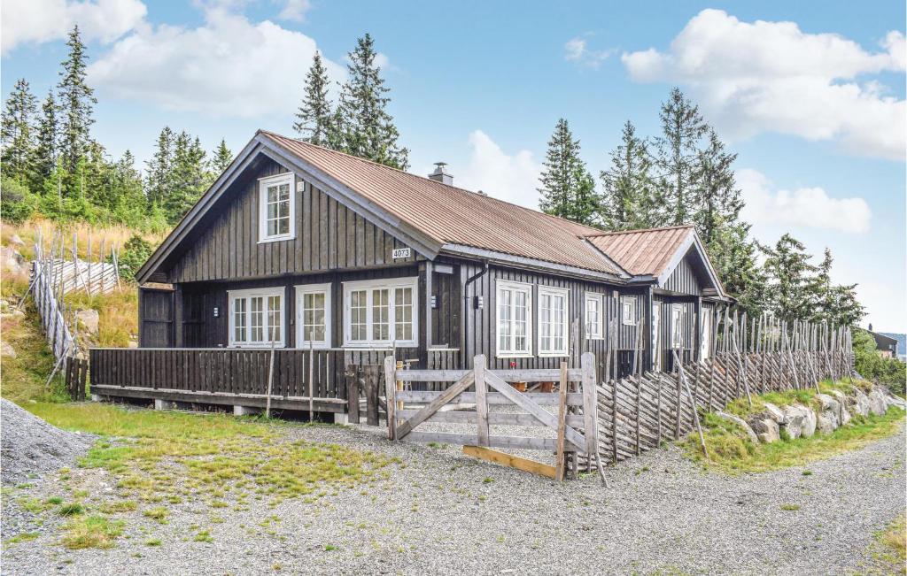 una casa de madera con una valla delante en Amazing Home In Sjusjen With Kitchen, en Sjusjøen