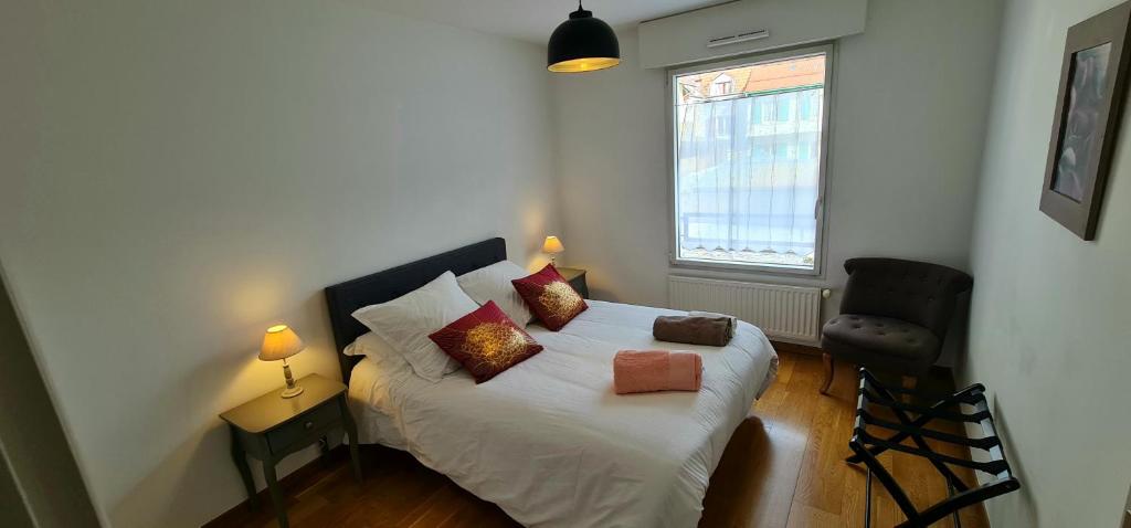 um quarto com uma cama branca com almofadas e uma janela em Appartement CITY CENTER-SALLANCHES em Sallanches