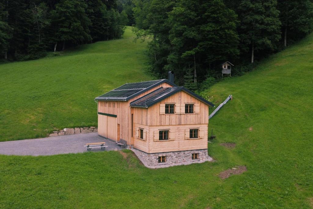 a house with a solar roof on a green field at Hirschberghütte in Bizau