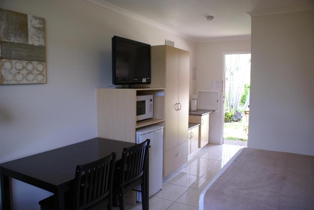 Una sala de estar con una mesa y un televisor en una pared. en Mackay Motor Inn, en Mackay
