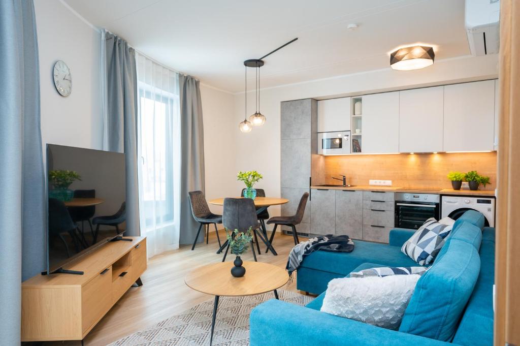 a living room with a blue couch and a kitchen at Aatrium Kinnisvara Riia str 20A apartment, 7-th floor in Tartu