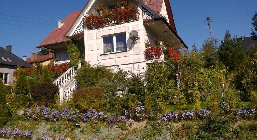 ein weißes Haus mit Blumen davor in der Unterkunft Dom Pod Różą in Leśna