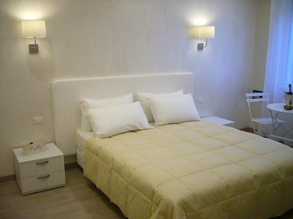 Schlafzimmer mit einem Bett mit weißer Bettwäsche und Kissen in der Unterkunft Grignetti Bed in Triest