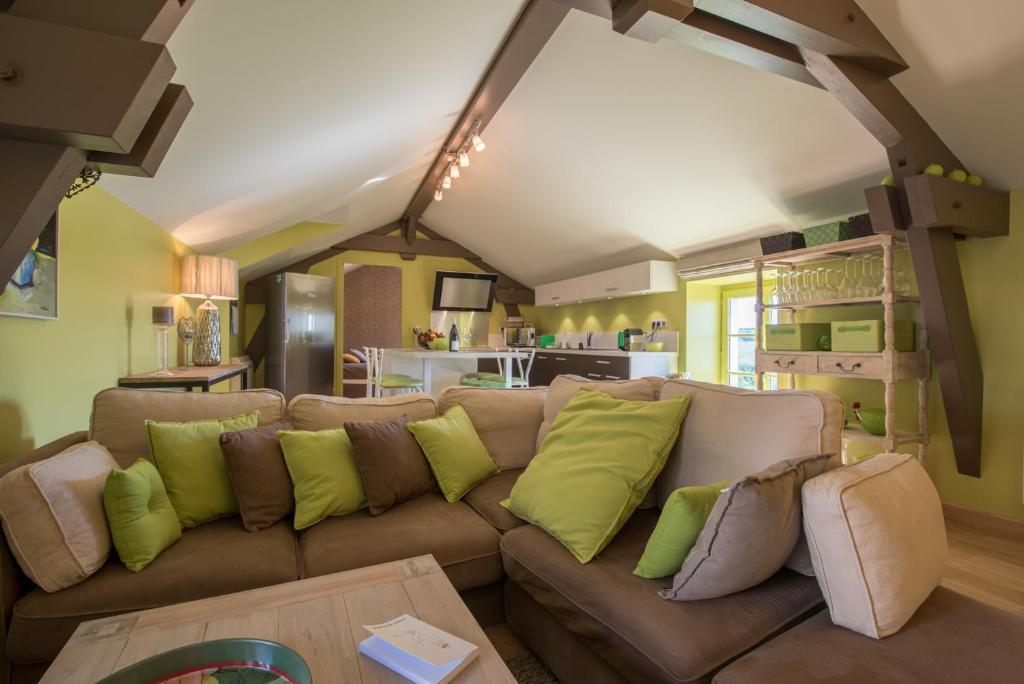 a living room with a brown couch with green pillows at Chez Joseph - Au coeur des vignes de Saint-Romain in Saint-Romain