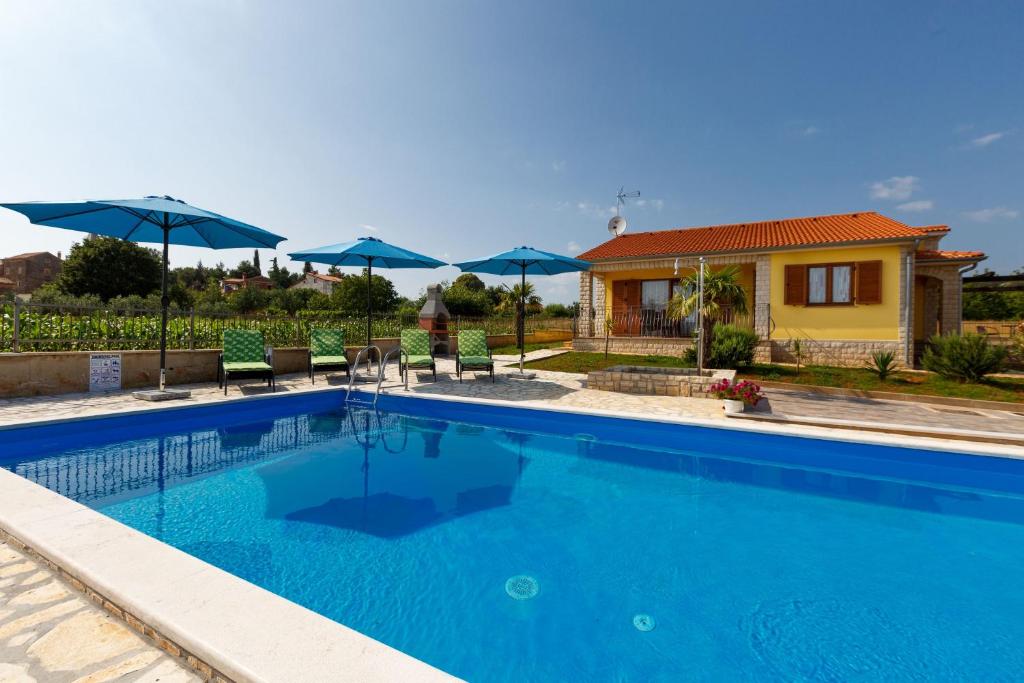 a swimming pool in front of a house with umbrellas at Villa Bali in Kaštelir