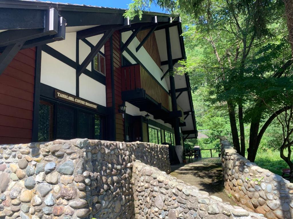 a building with a stone fence in front of it at Tanigawa Valley Lodge & Coffee Roastery in Minakami