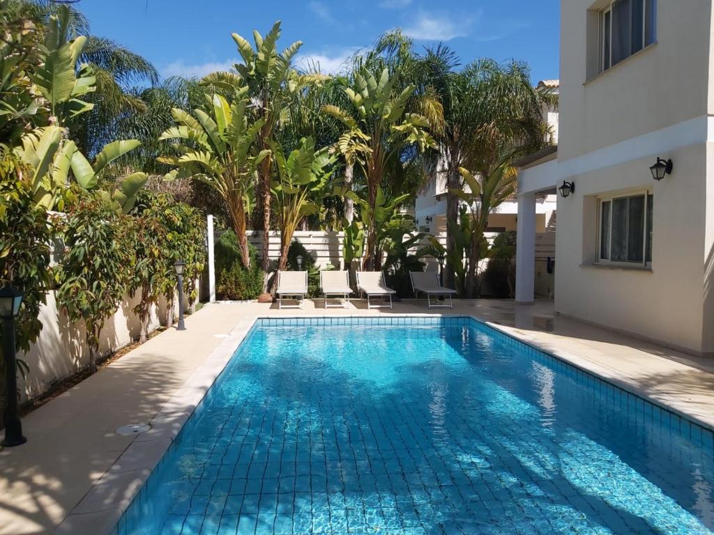 a swimming pool in the backyard of a house with palm trees at Anthorina 21 in Protaras