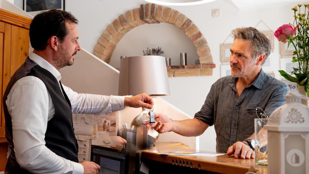 Un uomo sta dando un bicchiere ad un altro uomo di Das Stadthaus a Neusiedl am See