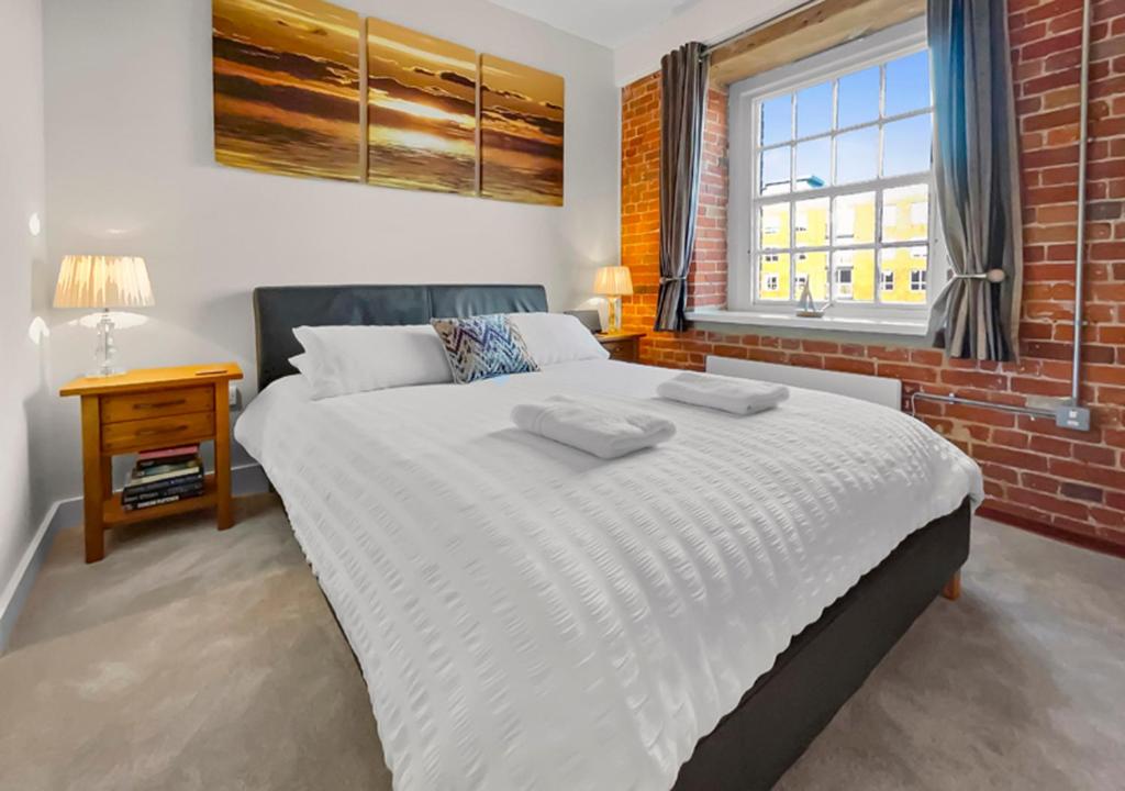 a bedroom with a large white bed with a brick wall at The Granary in Gosport