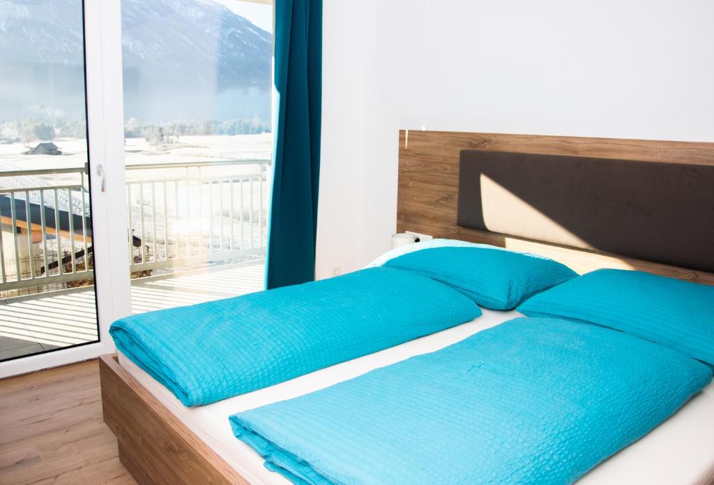 Una cama con almohadas azules en una habitación con balcón. en Landhaus Juleiko en Nassereith