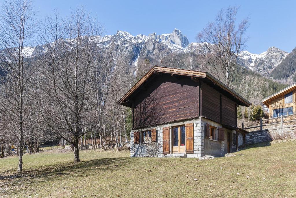 une petite maison dans un champ avec des montagnes en arrière-plan dans l'établissement Petit Chalet Des Moussoux - Happy Rentals, à Chamonix-Mont-Blanc