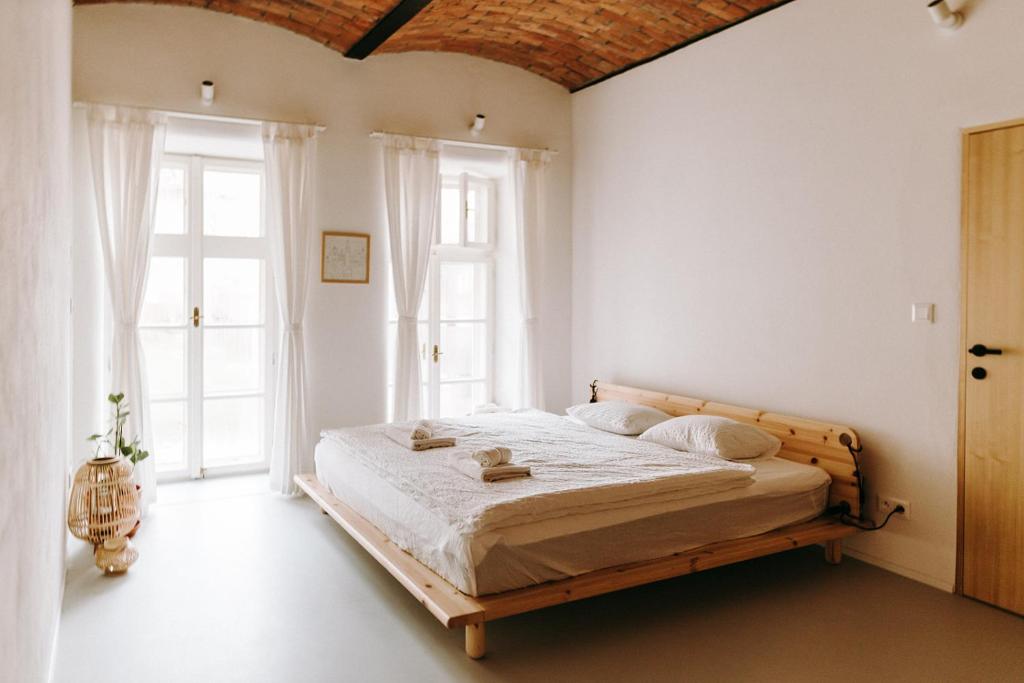 a bedroom with a wooden bed in a room with windows at Apartmány Starák v historickém centru Znojma in Znojmo