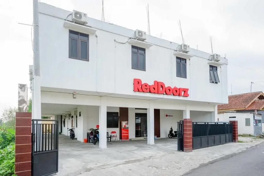 a white building with a red block sign on it at RedDoorz Syariah near Universitas Jenderal Soedirman 2 in Purwokerto