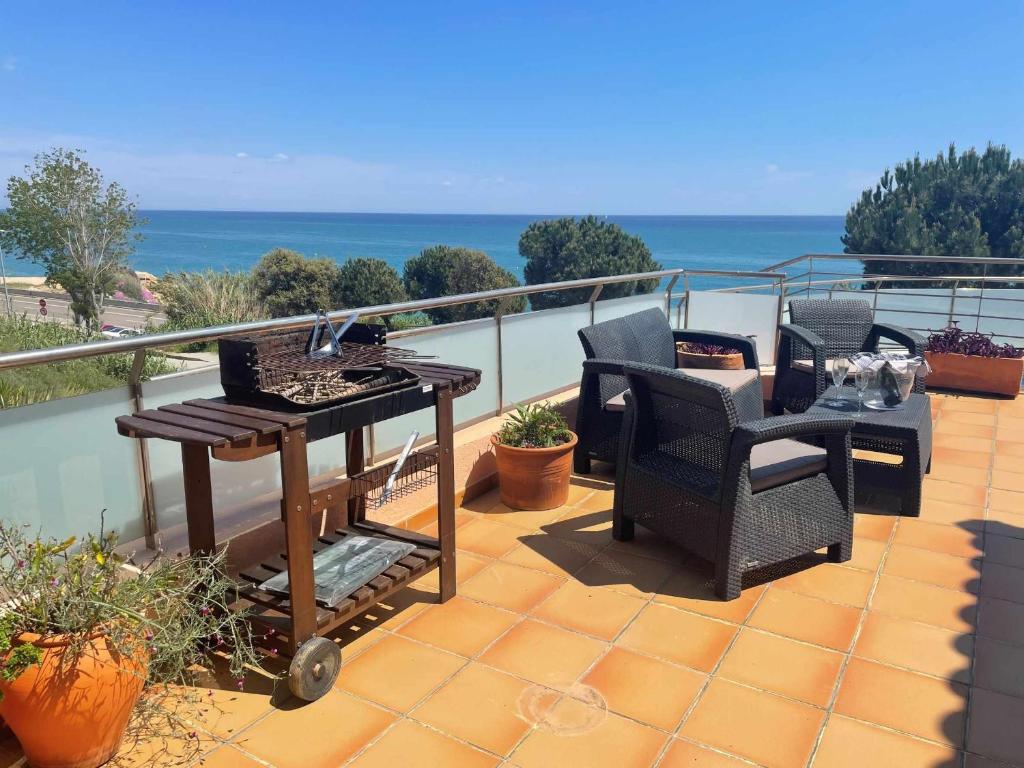 a patio with two chairs and a grill on a balcony at Villa Farell just in front of the sea in San Pol de Mar