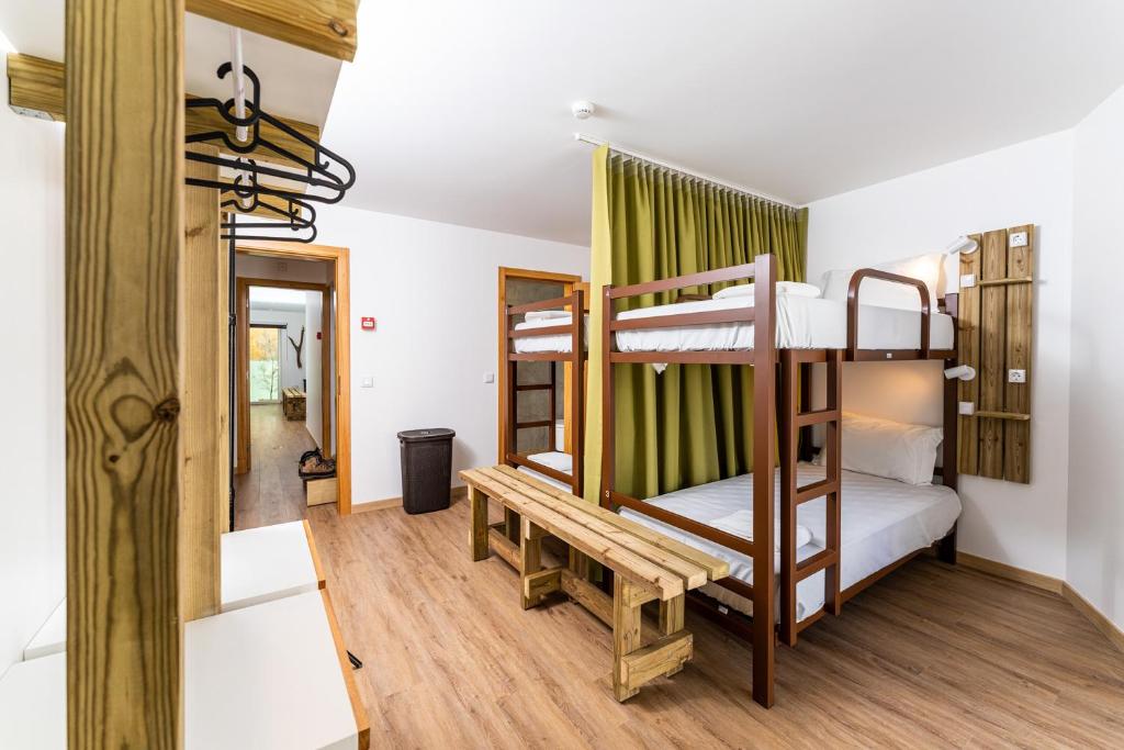 カミーニャにあるOlá Vida - Hostel Caminhaの二段ベッド2台とベンチが備わる客室です。