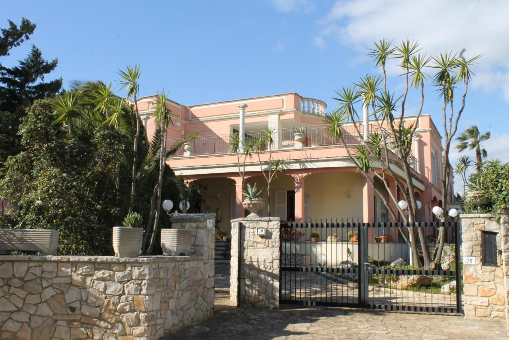 a pink house with a gate and palm trees at Villa la Bifora by Salento com in Castrignano del Capo