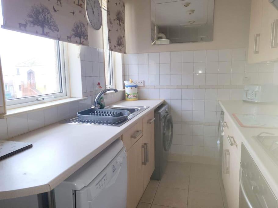 a kitchen with a sink and a washing machine at Homely Apartment near the Beach with Mini Luxuries in Methil