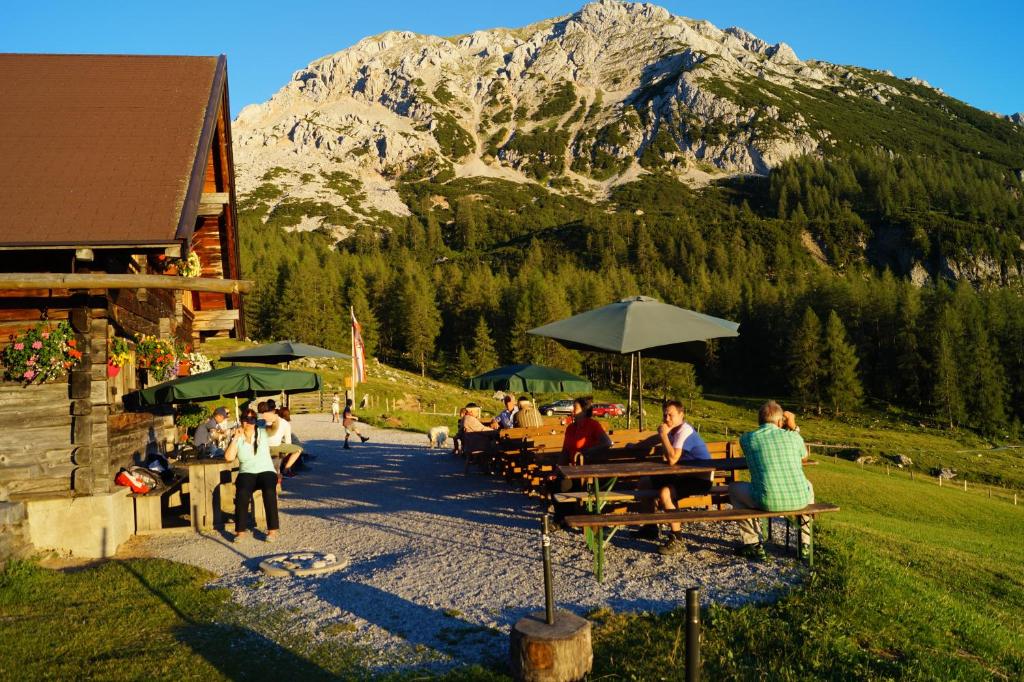 a group of people sitting at tables in front of a mountain at Appartement Hanneshof in Filzmoos