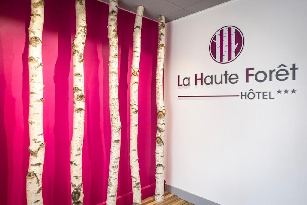 Pokój z różowymi zasłonami i znakiem hotelowym w obiekcie Logis hôtel restaurant la Haute Forêt w mieście Vertou