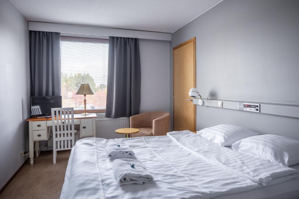 1 dormitorio con cama, escritorio y ventana en Budget Hotel Karhu, en Sodankylä