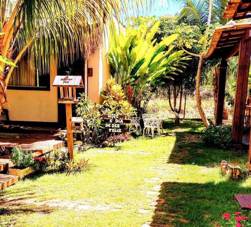 a garden with a house with palm trees and a table and chairs at Home suíte taipu in Marau
