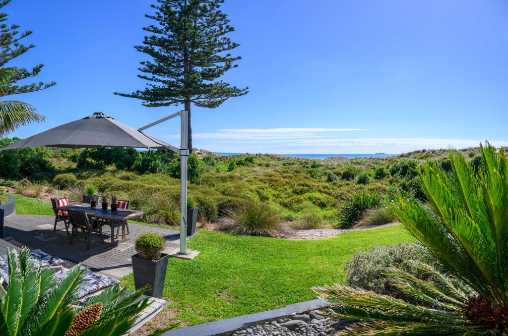 a patio with a table and an umbrella at Absolute Beach in Mount Maunganui