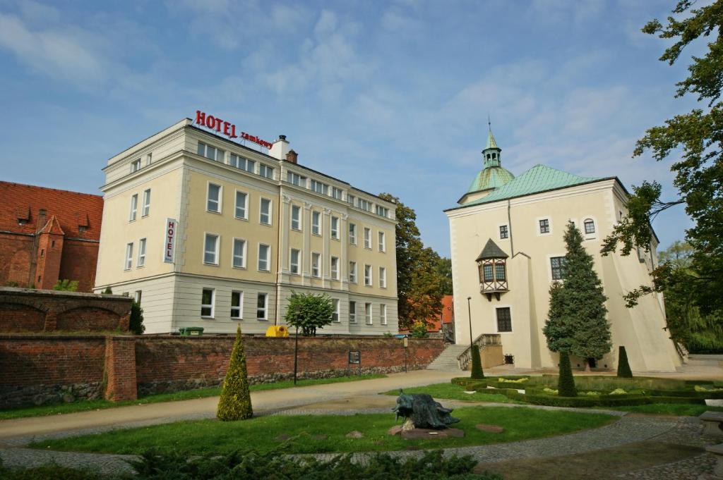 Biały budynek z czerwonym znakiem na górze w obiekcie Hotel Zamkowy w mieście Słupsk
