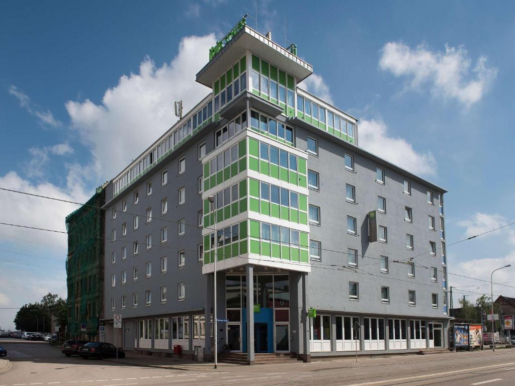 un gran edificio gris con ventanas verdes en una calle en ibis Styles Halle, en Halle an der Saale