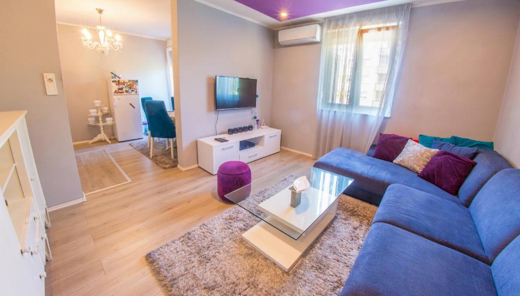 uma sala de estar com um sofá azul e uma televisão em Apartment Focus em Mostar