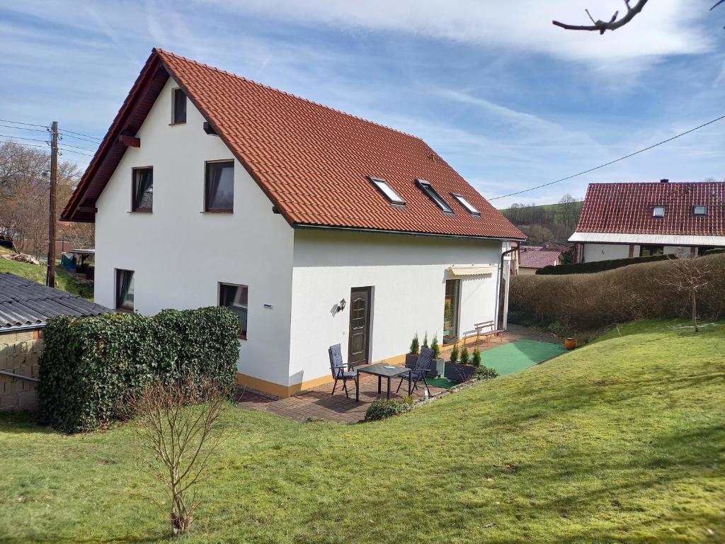 ein weißes Haus mit einem Tisch und Stühlen im Hof in der Unterkunft Ferienwohnung Schmalkalden am Radwanderweg in Schmalkalden