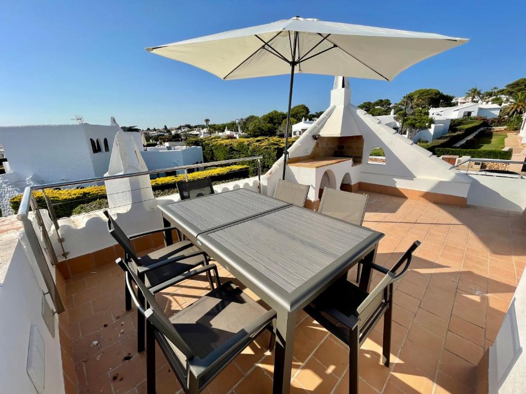 a table and chairs with an umbrella on a roof at Casa la Marinera in Binibeca