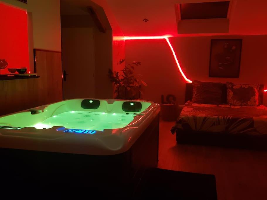un bagno con vasca e un letto con luci rosse di Bulles étoilées Appartement avec jacuzzi privé a Montrevel-en-Bresse
