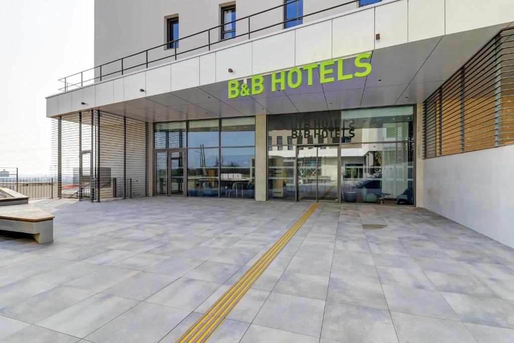 - un grand bâtiment avec un grand panneau d'hôtels dans l'établissement B&B HOTEL Dijon Valmy Toison d'or, à Dijon