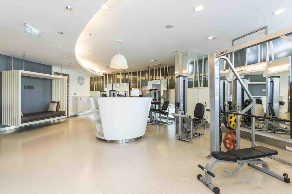 A bright fitness room has weight machines, a cable station and cardio equipment.