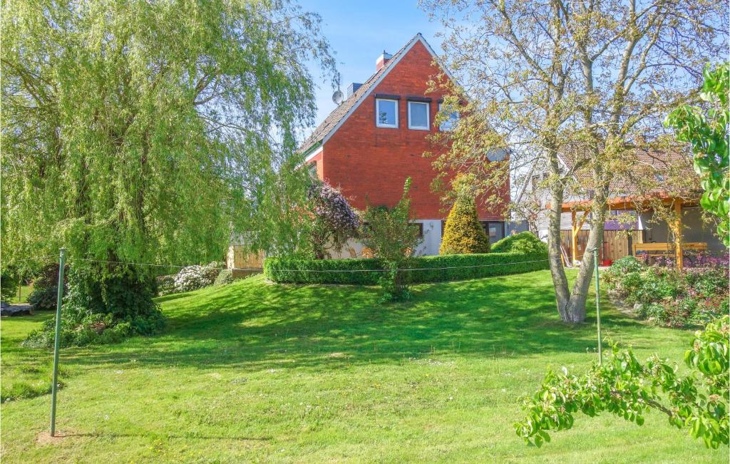a red house with a green yard in front of it at Awesome Home In Drochtersen With Kitchen in Drochtersen