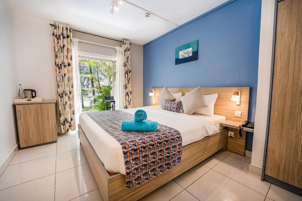 Schlafzimmer mit einem Bett mit blauer Wand in der Unterkunft Le Grand Bleu Hotel in Trou aux Biches