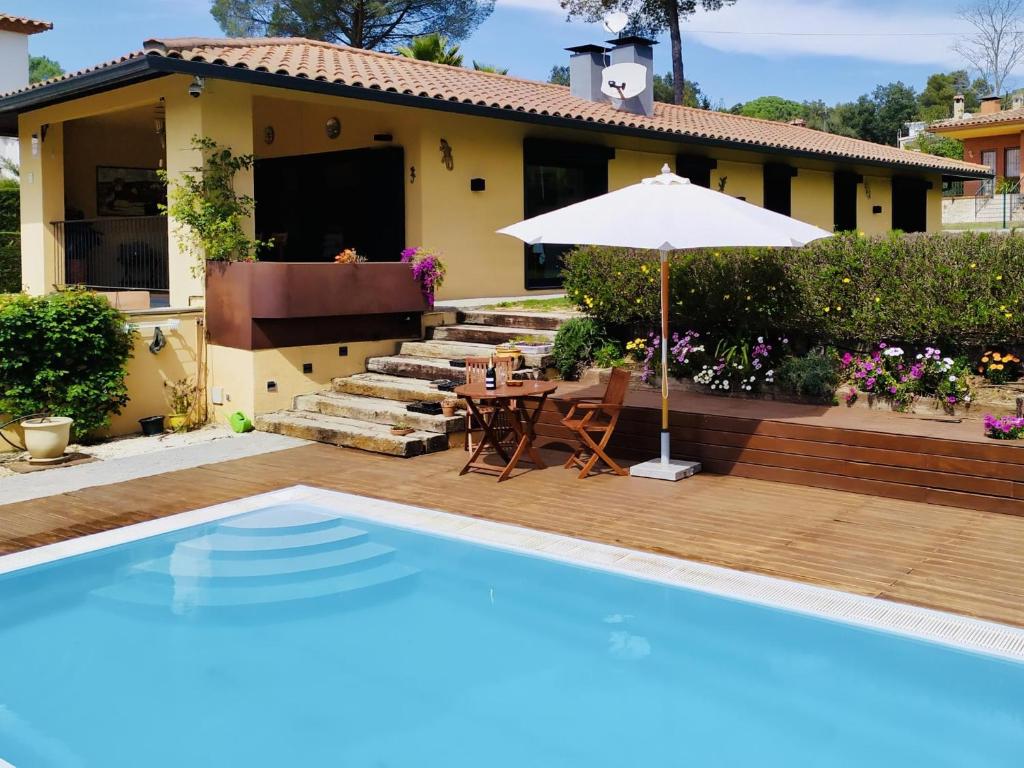 a house with a swimming pool and an umbrella at Villa Serena in Santa Cristina d'Aro