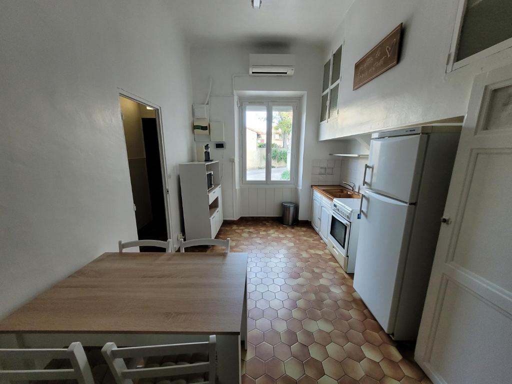 Il comprend une cuisine équipée d'une table et d'un réfrigérateur. dans l'établissement Adorable Maison en plein cœur du village., à Bouc-Bel-Air