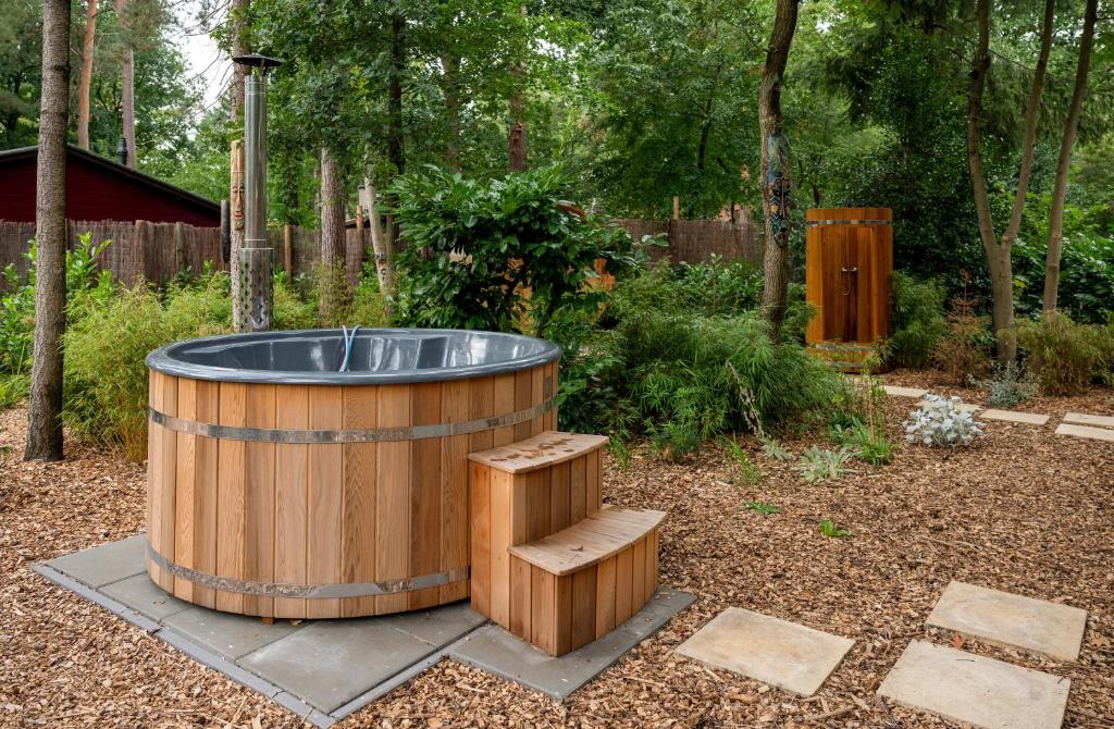 een houten hottub met een houten bank in een tuin bij ZEN-Bungalow NO 4 met sauna en hottub in Rheezerveen