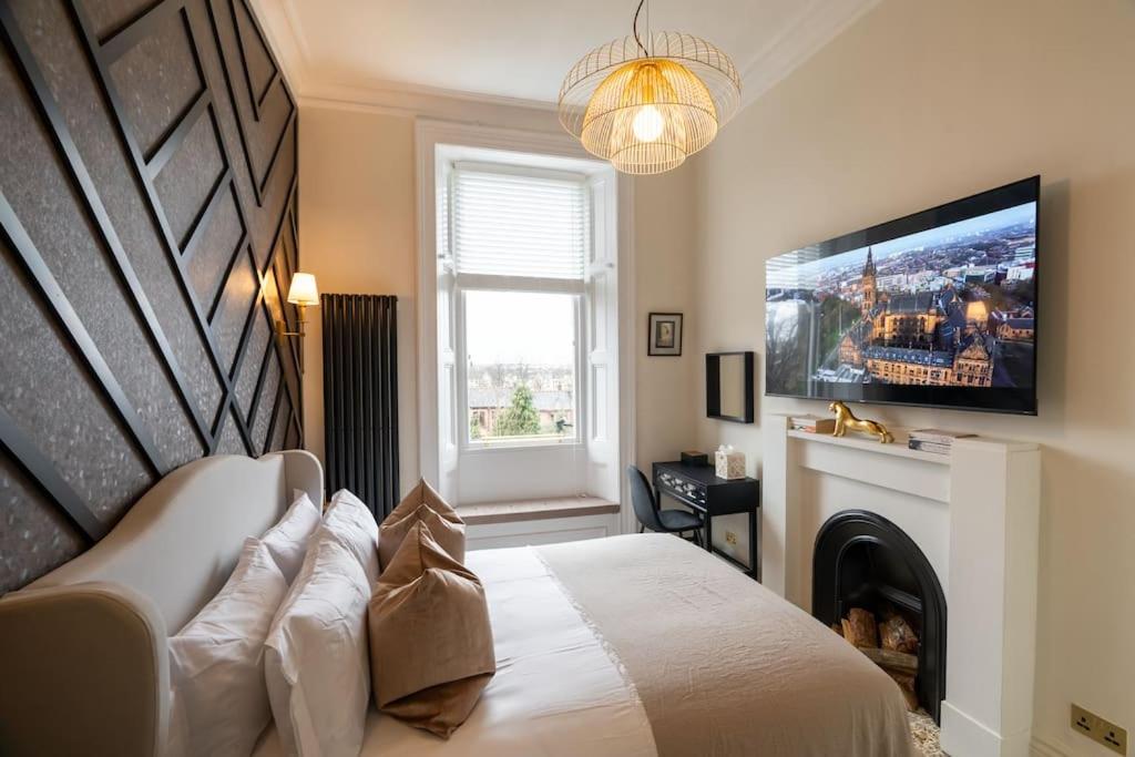a bedroom with a bed with a tv and a fireplace at The Devonshire Suite - Your 5 STAR West End Stay! in Glasgow