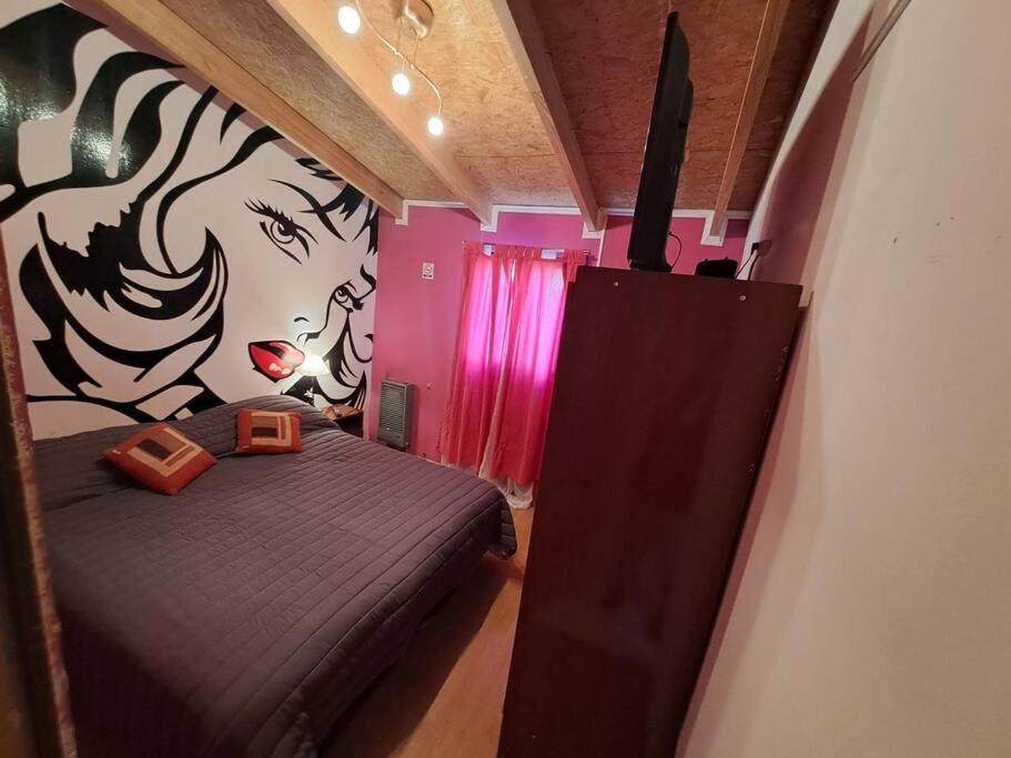 una habitación con una cama y una pintura de una mujer en Ana y Pali en Ushuaia