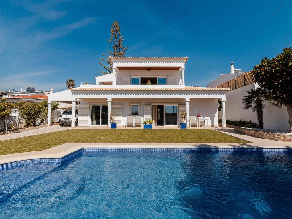 a villa with a swimming pool in front of a house at Fantastic four-bedroom villa in Praia da Luz with private pool in Caliços
