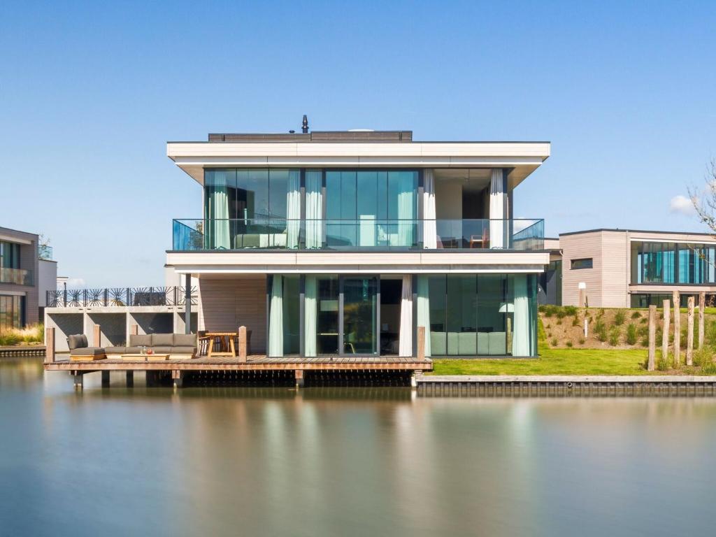 a house on a dock on a body of water at Luxury villa with boathouse on the Veerse Meer in Arnemuiden