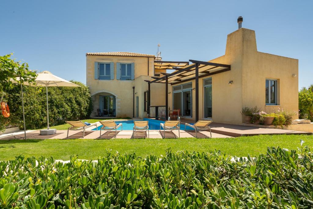 una casa con un patio con sillas y una piscina en Calma Seaside Villa, en Kalyves