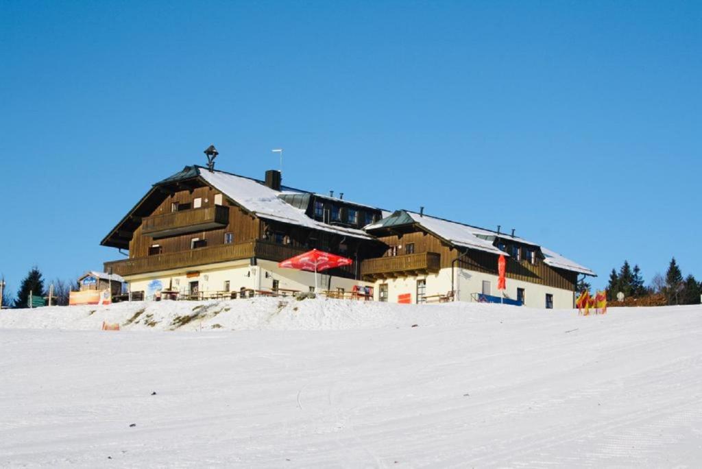 un gran edificio situado en la cima de una ladera cubierta de nieve en Almberghütte en Philippsreut