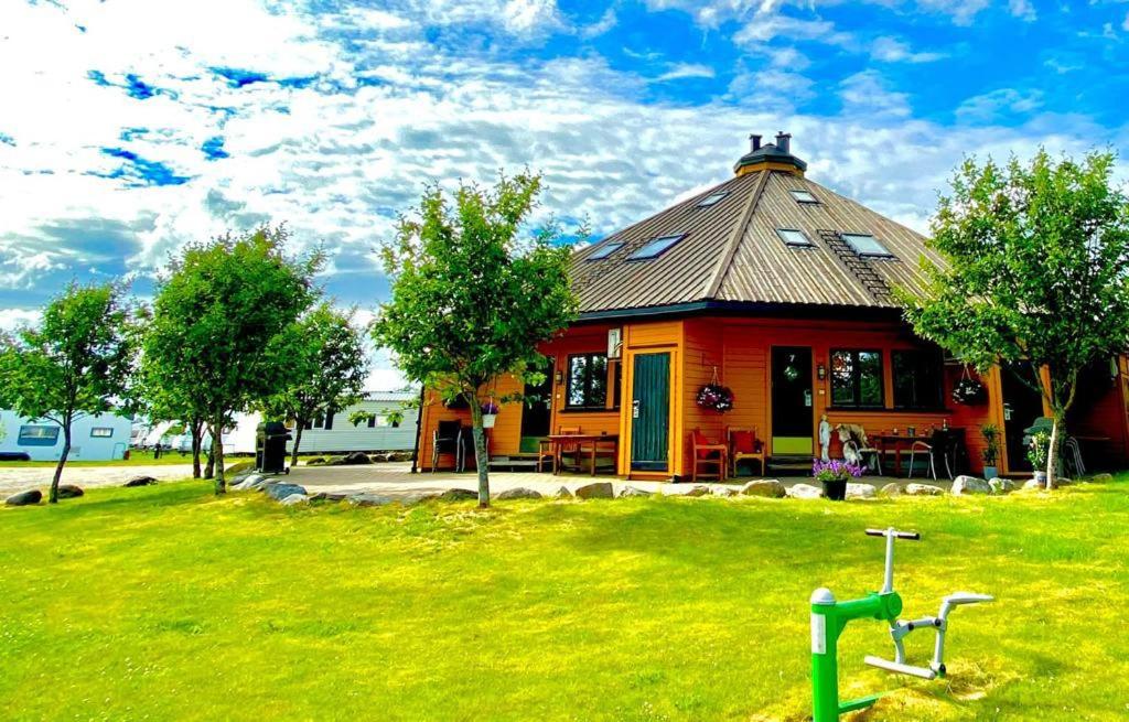 um edifício vermelho com um telhado num campo verde em Sarpsborg Apartments - Utne Camping em Solli