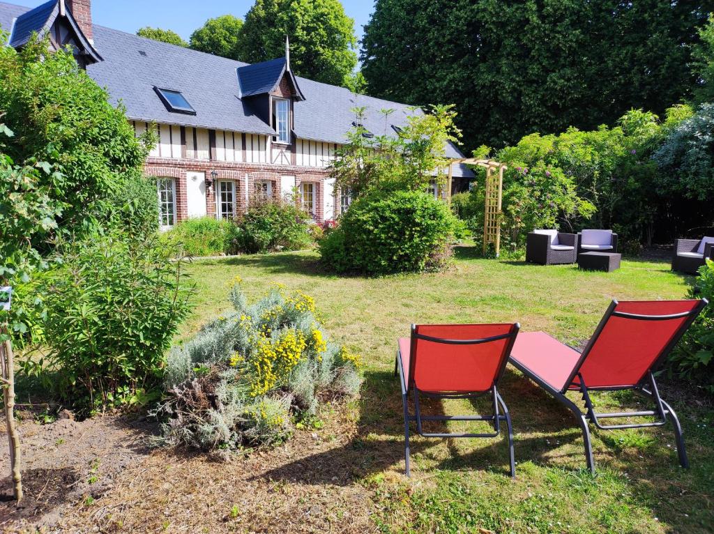 two chairs and a table in front of a house at Le Relais Des Dalles in Sassetot-le-Mauconduit