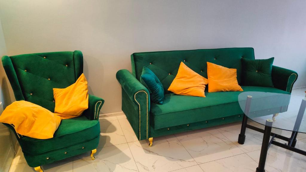 a green couch and two chairs with yellow pillows at Apartament u Danusi in Złoty Stok