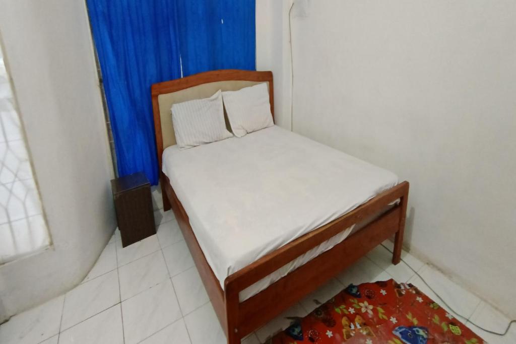 ein kleines Bett in einem Zimmer mit einem blauen Vorhang in der Unterkunft SPOT ON 92390 Wilma Kost Syariah in Banjarmasin